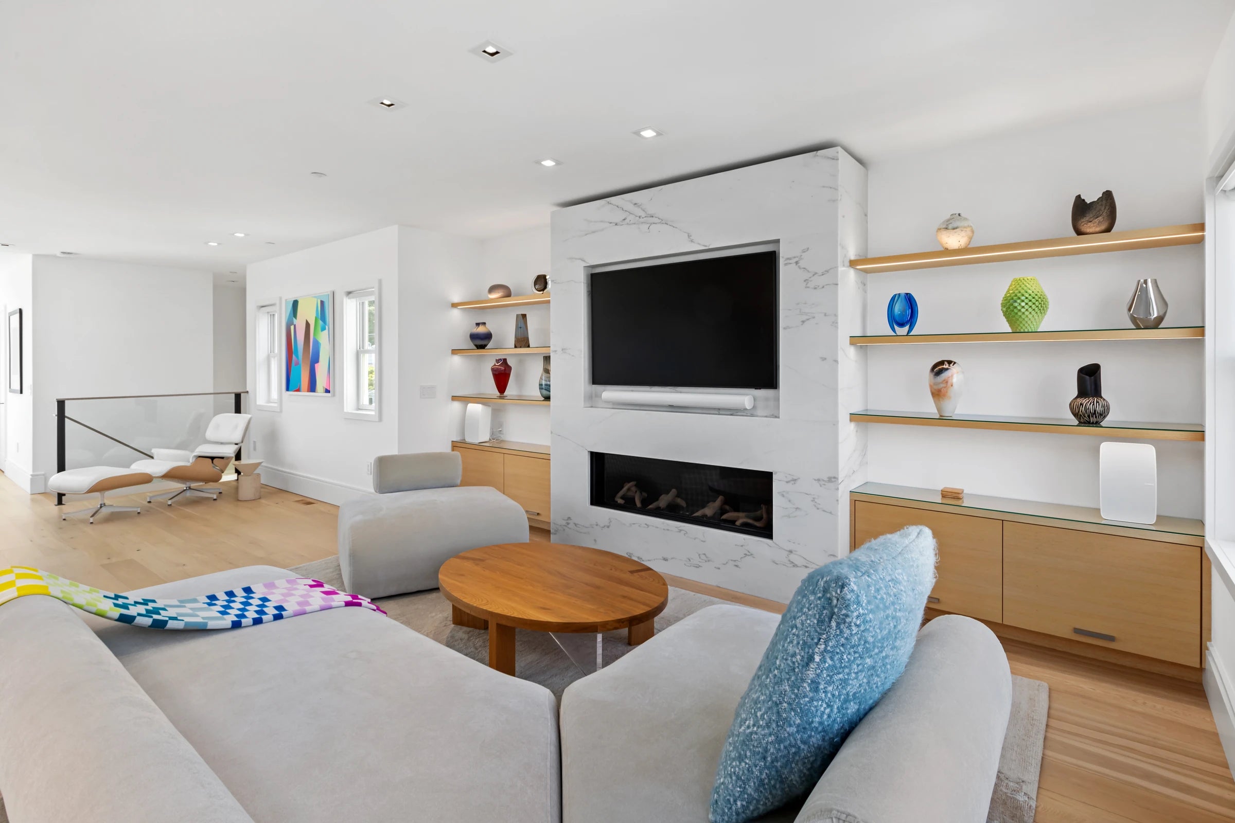 Natural wood living-room built-ins and illuminated display shelves framing a stone fireplace