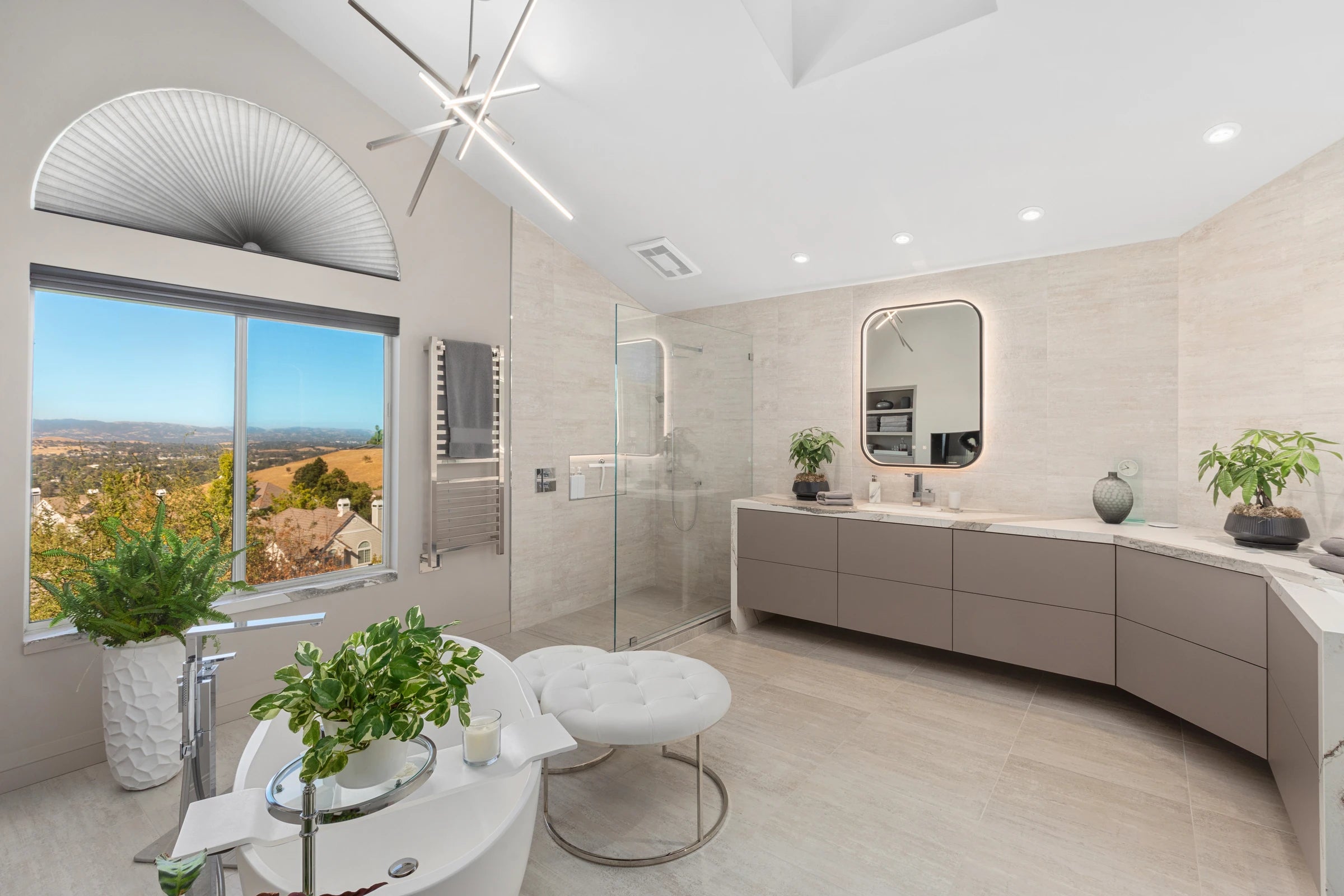 Full view of a custom taupe bathroom vanity with a stone countertop, backlit mirror and large window at 412 Wawona